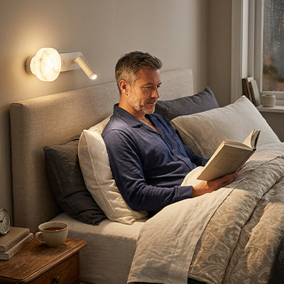 homme lit livre sous appliques murale design